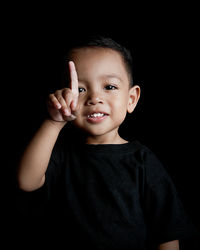 Portrait of cute boy against black background