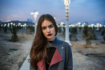 Portrait of beautiful woman standing against city in background