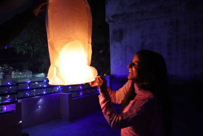 Side view of woman holding lit candles at night