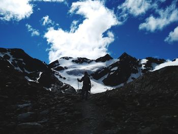 Low angle view of silhouette man hiking on snowcapped mountain against sky