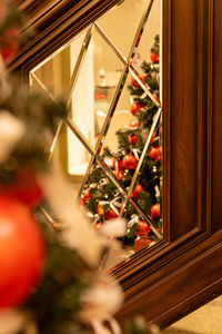 Winter holidays interior decoration. christmas tree with red baubles in mirror of the fooden ladder.