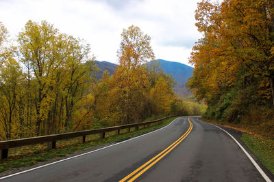 Road amidst trees against sky during autumn
