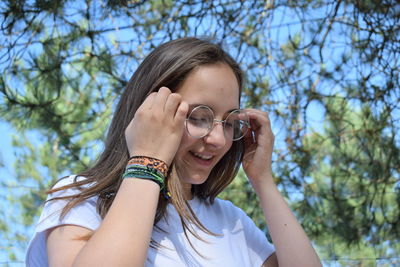 Portrait of young woman wearing sunglasses against trees