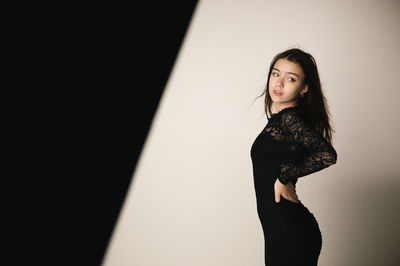 Portrait of young woman standing against wall