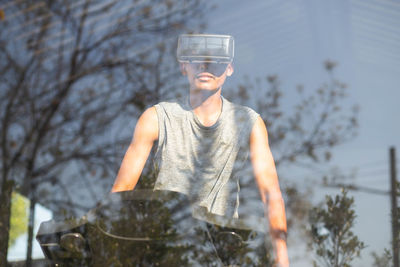 Young man wearing virtual reality simulator exercising at gym