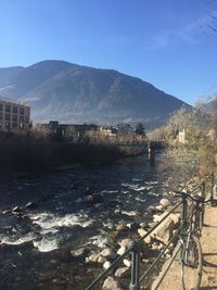 Scenic view of river by buildings against sky