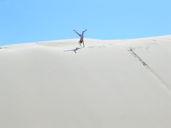 Low angle view of man practicing handstand on sand dune