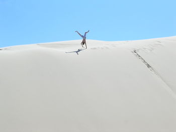 Low angle view of man practicing handstand on sand dune