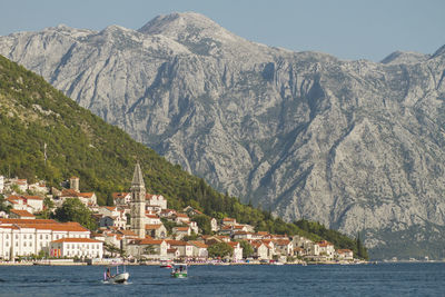 Scenic view of sea by town against sky and mountains