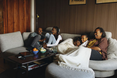 Happy family sitting together on sofa in living room at home