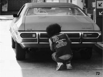 Rear view of boy with car on street in city