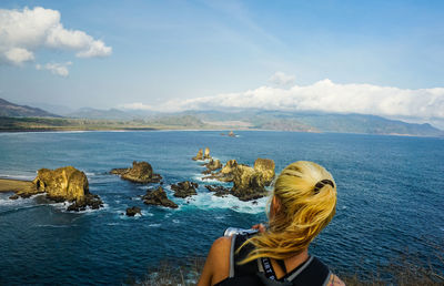 Rear view of woman photographing sea against sky