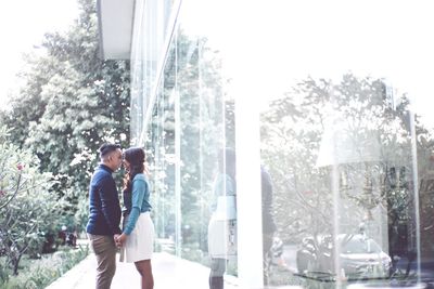 Couple standing against trees and plants