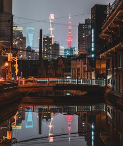 Illuminated bridge over river in city at night