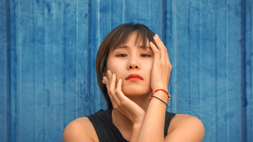 Close-up portrait of woman against blue wall