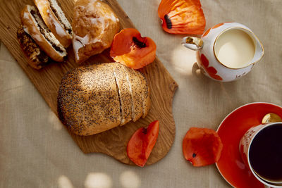 Traditional poppy seed buns, cup of black tea and milk. poppies and dishes with poppies ornaments. 