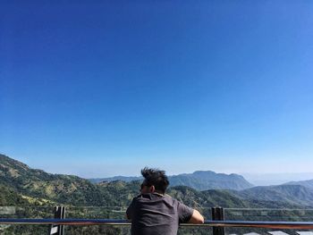 Man photographing against clear blue sky