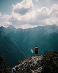 Rear view of man standing on mountain against sky