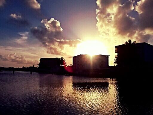 sunset, sun, building exterior, sky, architecture, water, built structure, silhouette, sunlight, reflection, waterfront, cloud - sky, sunbeam, lens flare, cloud, scenics, beauty in nature, nature, river, tranquility