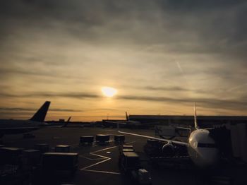 Airplane on runway against sky during sunset