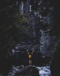 Woman standing on rock by river in forest