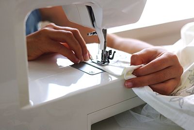 Close-up of human hand using sewing machine