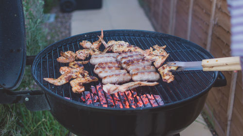 High angle view of chicken wings and sausages on barbecue grill