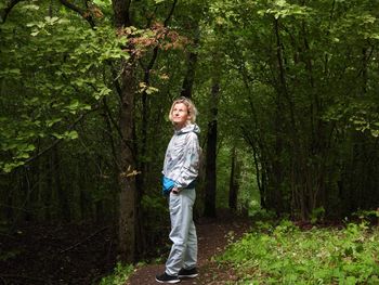 Portrait of smiling girl standing by tree in forest