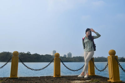 Full length of woman standing on promenade against blue sky