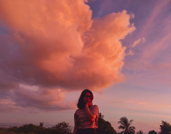 Woman standing on field against sky during sunset