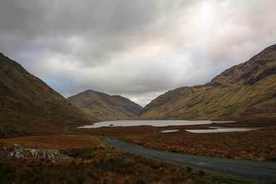 Scenic view of road by mountains against sky