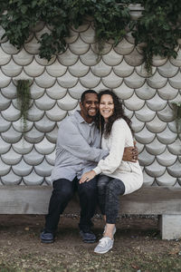 Married couple sitting on park bench smiling and hugging