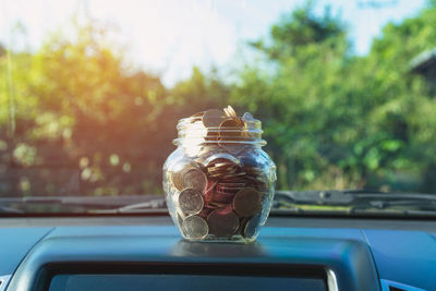 Close-up of coin jar on car windshield