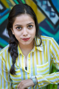 Portrait of young woman with red lipstick standing against wall