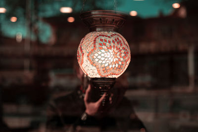 Close-up of person holding illuminated lighting equipment at night