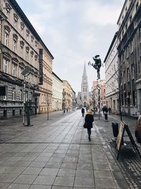 Rear view of man walking on road in city