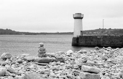 Lighthouse by sea against sky