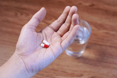 Cropped hand holding medicines over table