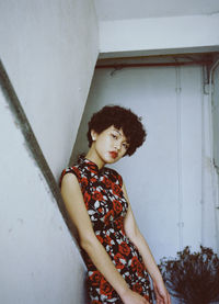 Portrait of young woman leaning by railing in building