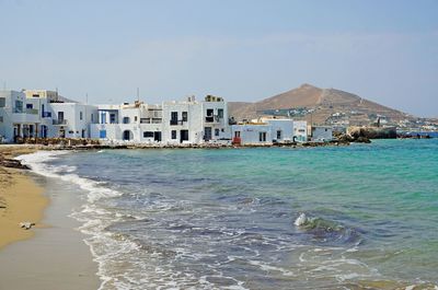 Buildings by sea against clear sky