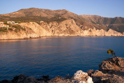 Scenic view of sea and mountains against clear sky