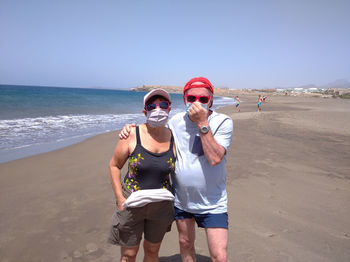 Portrait of young couple on beach against sea against sky