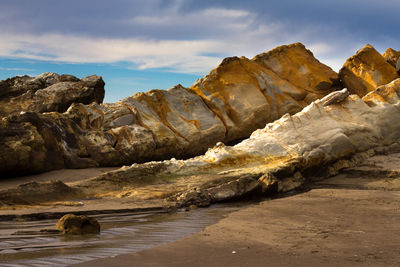 Rock formation on beach against sky