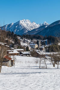 Snow covered buildings and mountains against clear sky