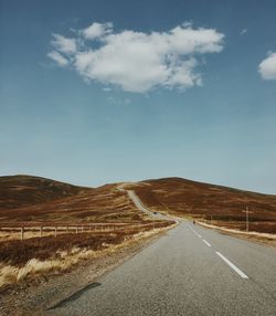 Empty road by mountain against sky