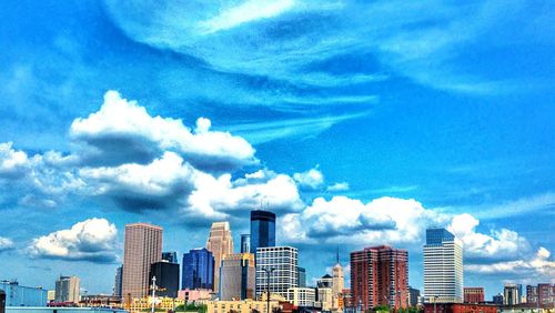 Low angle view of skyscrapers against cloudy sky