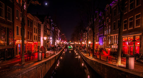 Panoramic view of illuminated street amidst buildings at night