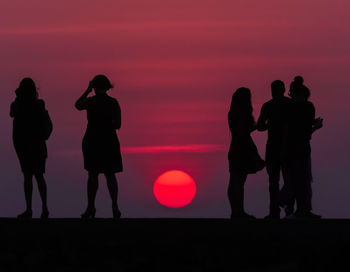 Silhouette people standing against sky during sunset