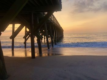 Pier over sea against sky during sunset