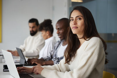 Smiling woman sitting during business meeting and looking at camera